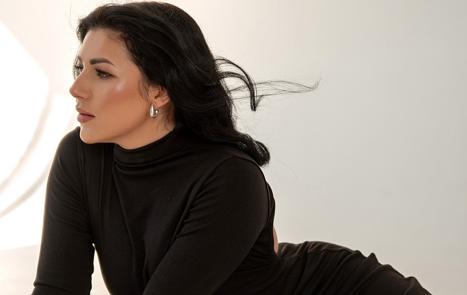 Woman in black outfit looking contemplatively sideways.